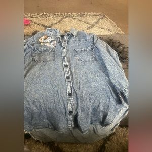 Blue acid wash Jean shirt,  faux leather fringe hanging from the back and arms.